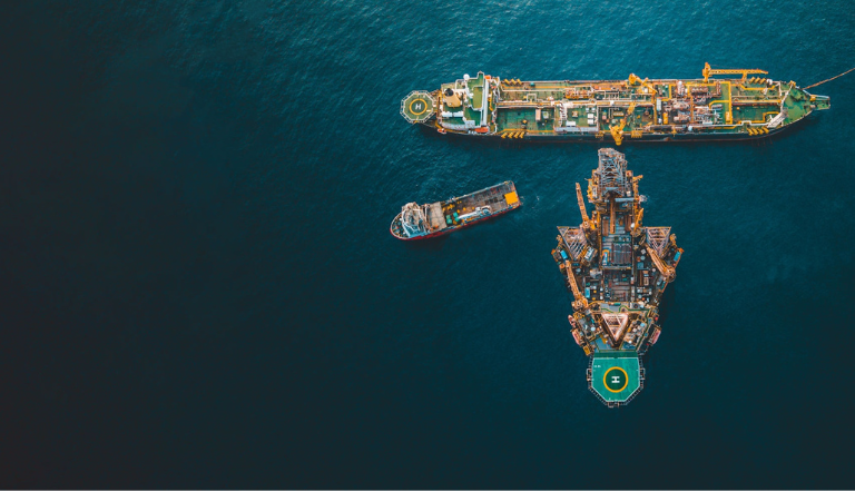 view from above 2 large ships beside an oil rig in the middle of calm deep blue sea